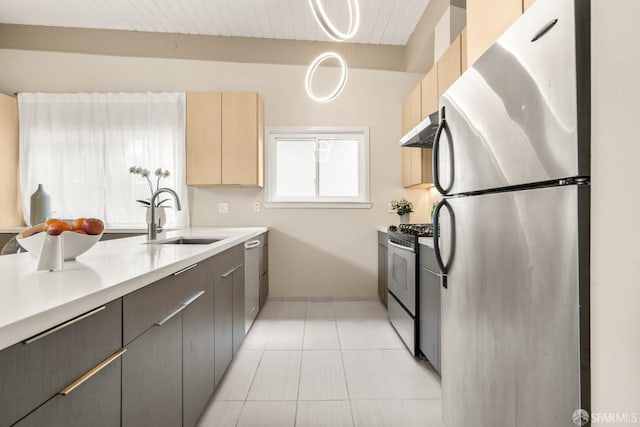 kitchen featuring under cabinet range hood, light countertops, light tile patterned floors, appliances with stainless steel finishes, and a sink