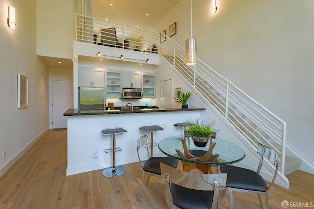 3118 18th St Unit 2, San Francisco, CA 94110 - kitchen featuring stainless steel appliances, a towering ceiling, light wood finished floors, dark stone counters, and recessed lighting