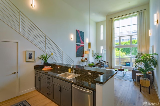 3118 18th St Unit 2, San Francisco, CA 94110 - kitchen featuring stainless steel dishwasher, a sink, light wood-type flooring, dark stone counters, and baseboards