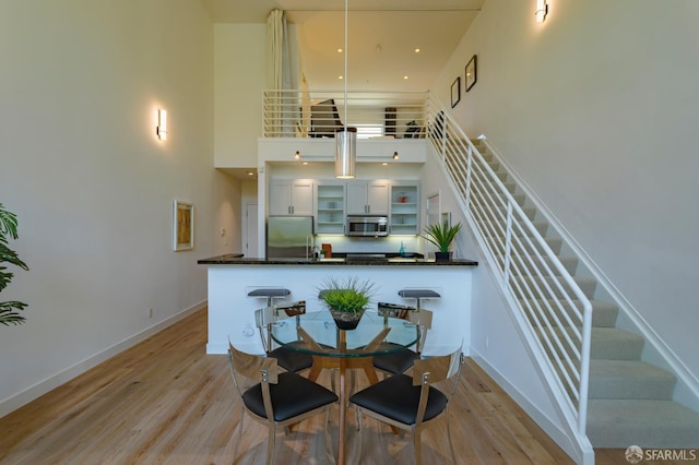 3118 18th St Unit 2, San Francisco, CA 94110 - dining area featuring a high ceiling, stairway, light wood finished floors, and baseboards