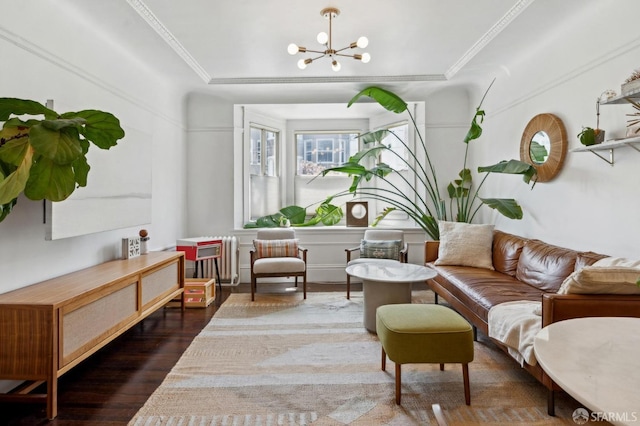 living room featuring wood finished floors, a chandelier, ornamental molding, and a tray ceiling