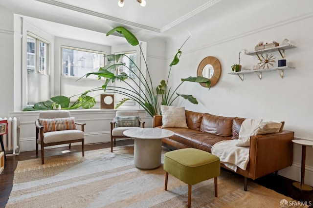 sitting room with wood finished floors, a decorative wall, ornamental molding, and a wainscoted wall