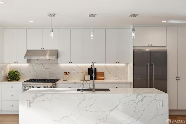 kitchen featuring pendant lighting, light wood-type flooring, white cabinets, stainless steel appliances, and light stone countertops