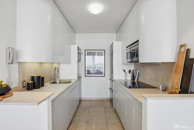 999 Green St Unit 1403, San Francisco, CA 94133 - kitchen featuring black electric cooktop, stainless steel microwave, white cabinetry, and tasteful backsplash