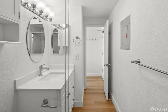 201 Harrison St Unit 302, San Francisco, CA 94105 - bathroom with electric panel, wood finished floors, a textured wall, vanity, and baseboards