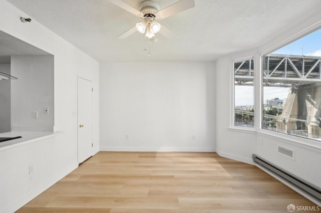 201 Harrison St Unit 302, San Francisco, CA 94105 - unfurnished dining area with light wood-style floors, a ceiling fan, a baseboard heating unit, a textured ceiling, and baseboards