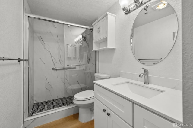 201 Harrison St Unit 302, San Francisco, CA 94105 - full bathroom featuring toilet, a marble finish shower, a textured ceiling, wood finished floors, and vanity