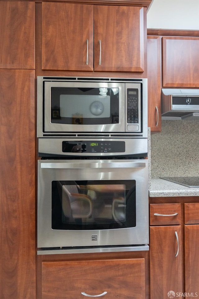 details featuring brown cabinetry, appliances with stainless steel finishes, extractor fan, and decorative backsplash