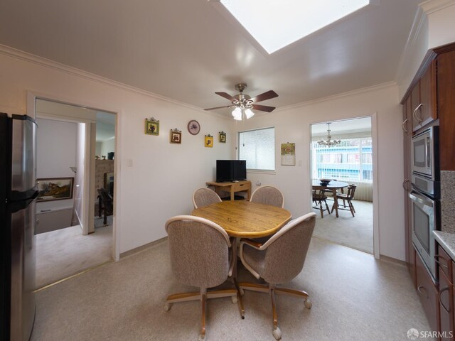 dining room with light colored carpet, crown molding, baseboards, and ceiling fan with notable chandelier