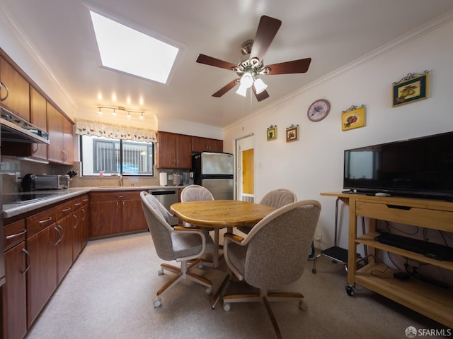 kitchen featuring a skylight, a sink, appliances with stainless steel finishes, tasteful backsplash, and crown molding