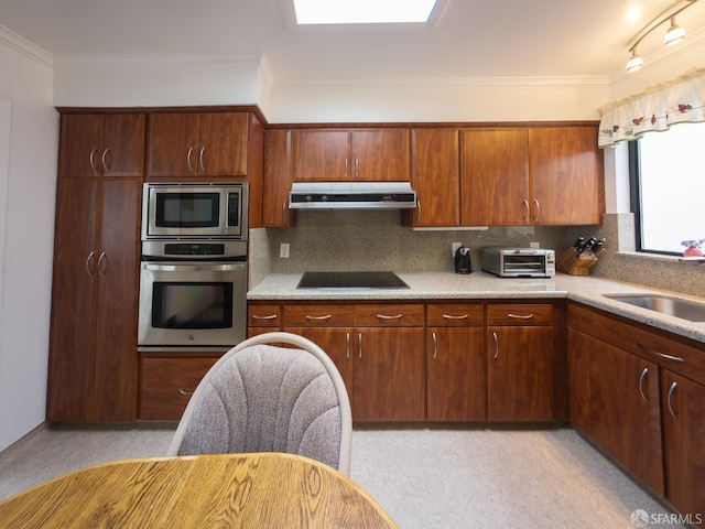 kitchen with tasteful backsplash, stainless steel appliances, light countertops, under cabinet range hood, and a sink