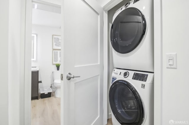 laundry area with stacked washing maching and dryer and light wood-type flooring