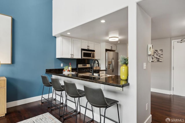 kitchen with white cabinetry, sink, a breakfast bar area, kitchen peninsula, and stainless steel appliances