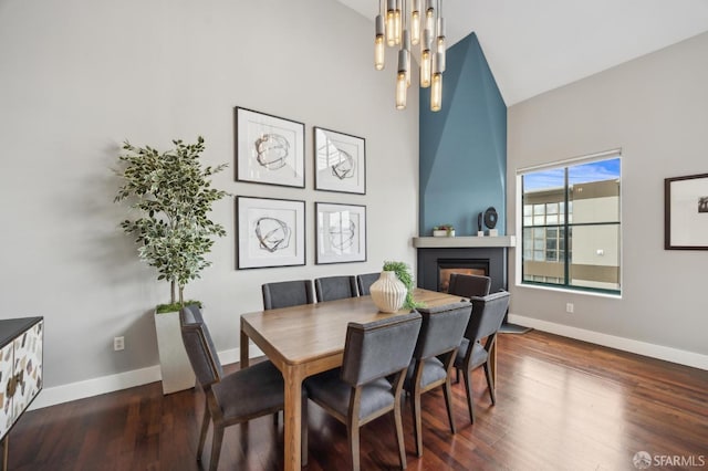 dining area featuring dark wood-type flooring, high vaulted ceiling, and a notable chandelier