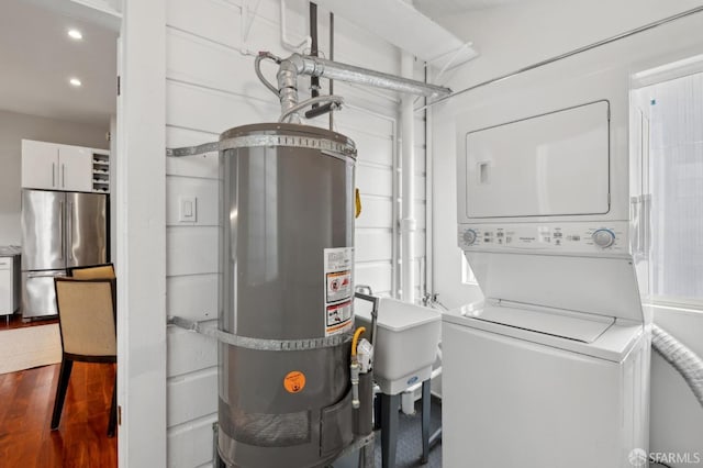 washroom with stacked washer and dryer, recessed lighting, water heater, a sink, and wood finished floors