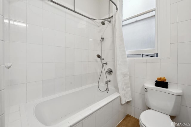 full bath featuring a healthy amount of sunlight, tiled shower / bath combo, tile walls, and toilet