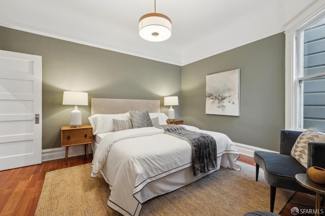 bedroom with ornamental molding, baseboards, and wood finished floors