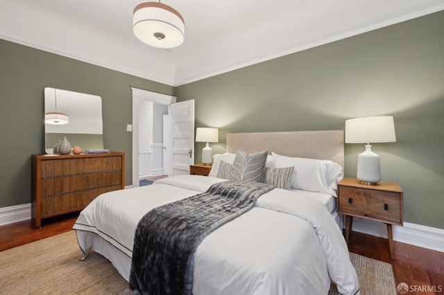 bedroom featuring baseboards, wood finished floors, and ornamental molding