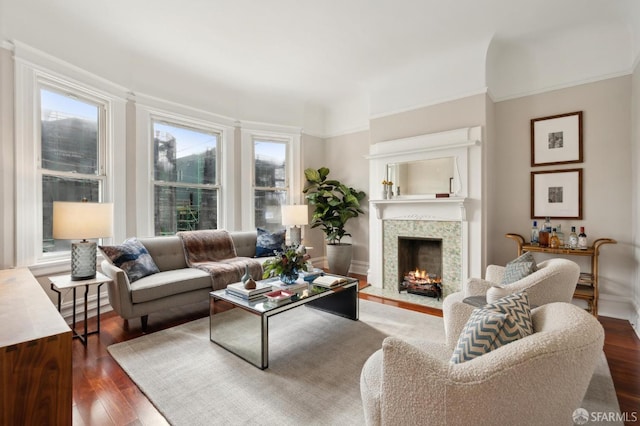 living room with a healthy amount of sunlight, a fireplace with flush hearth, ornamental molding, and dark wood-style flooring