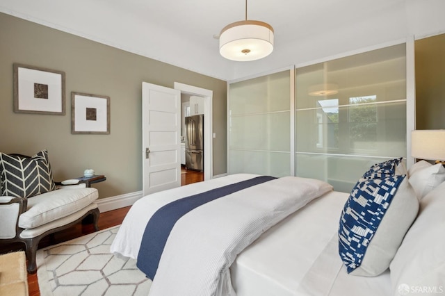 bedroom featuring freestanding refrigerator, baseboards, and wood finished floors