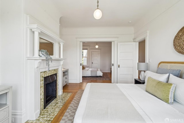 bedroom featuring wood finished floors and a tile fireplace