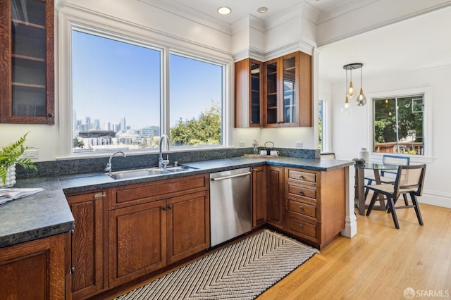 kitchen with pendant lighting, dark countertops, a sink, light wood finished floors, and dishwasher