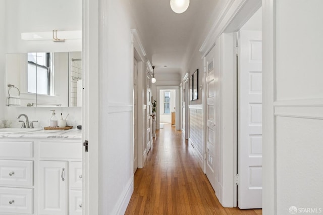 hallway with a sink, plenty of natural light, and light wood-type flooring