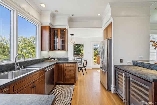 kitchen with a sink, light wood-style floors, plenty of natural light, stainless steel appliances, and wine cooler