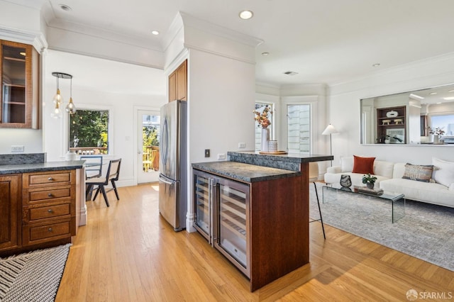 kitchen featuring dark countertops, freestanding refrigerator, open floor plan, wine cooler, and a breakfast bar