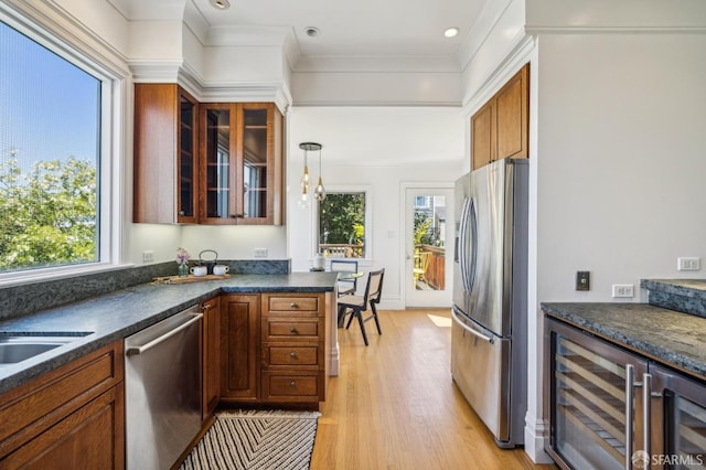 kitchen with dark countertops, stainless steel appliances, beverage cooler, and a wealth of natural light