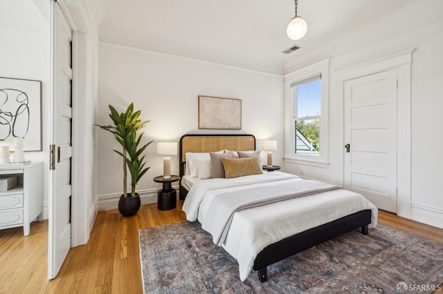 bedroom with visible vents, light wood finished floors, and baseboards