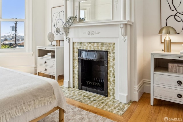 bedroom featuring multiple windows, wood finished floors, and a fireplace