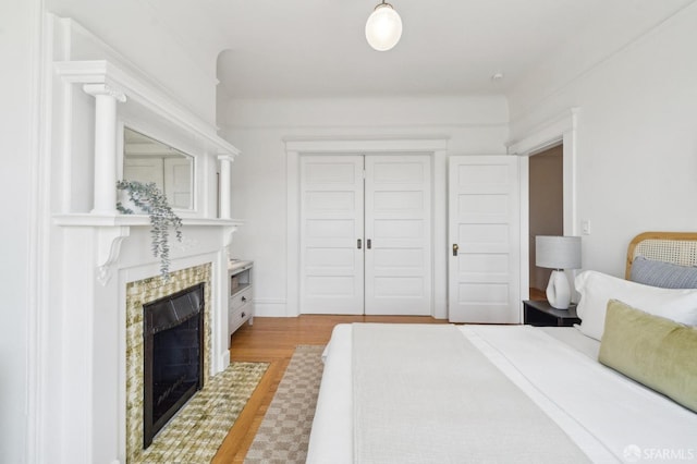 bedroom featuring a closet, wood finished floors, and a premium fireplace