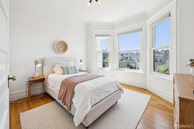 bedroom with baseboards, multiple windows, and light wood finished floors