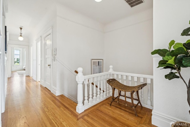 stairway featuring visible vents, baseboards, and wood finished floors