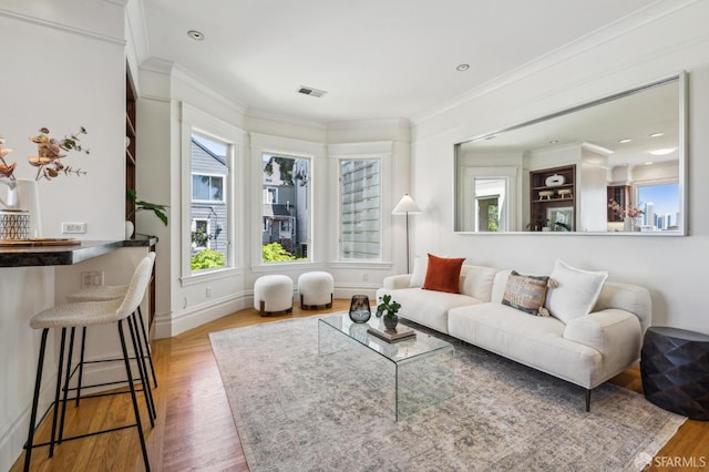 living room with visible vents, ornamental molding, wood finished floors, and a wealth of natural light