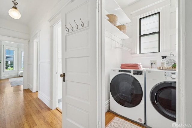 clothes washing area featuring light wood-type flooring, baseboards, and washer and dryer
