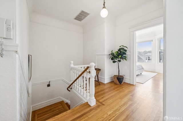 stairs with visible vents, baseboards, and wood finished floors