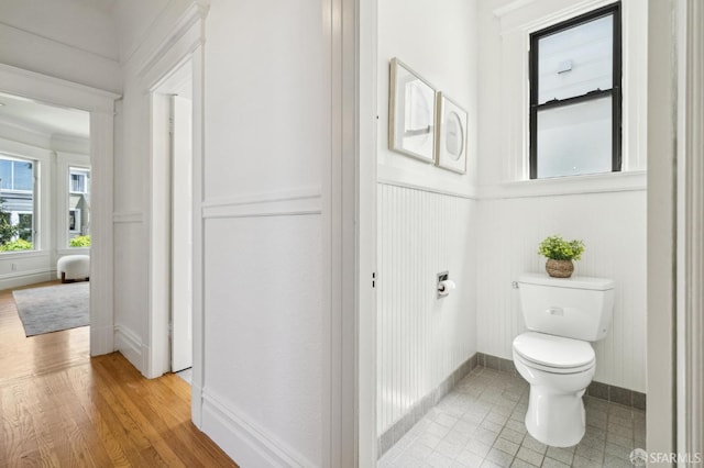 bathroom with baseboards, a decorative wall, a wainscoted wall, and toilet