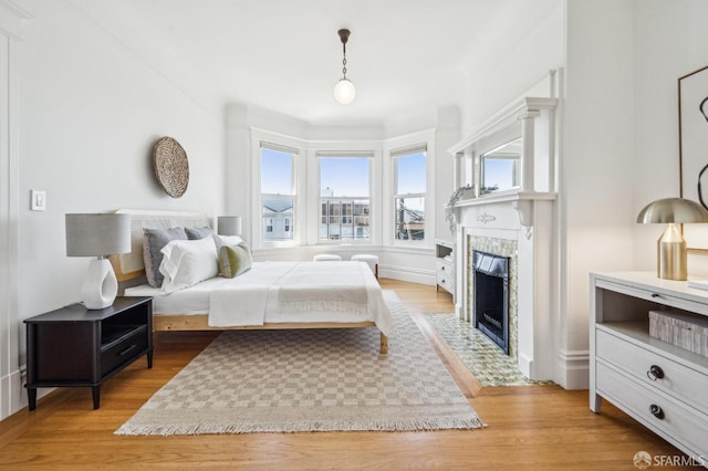 bedroom featuring a tiled fireplace and light wood-style floors