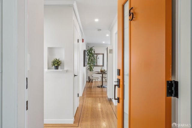 hall with light wood-type flooring and crown molding