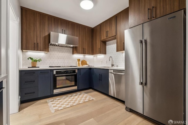835 Diamond St, San Francisco, CA 94114 - kitchen with appliances with stainless steel finishes, ventilation hood, light countertops, tasteful backsplash, and light wood-style flooring