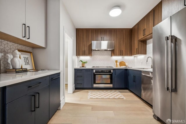 835 Diamond St, San Francisco, CA 94114 - kitchen with appliances with stainless steel finishes, range hood, tasteful backsplash, a sink, and light wood-type flooring