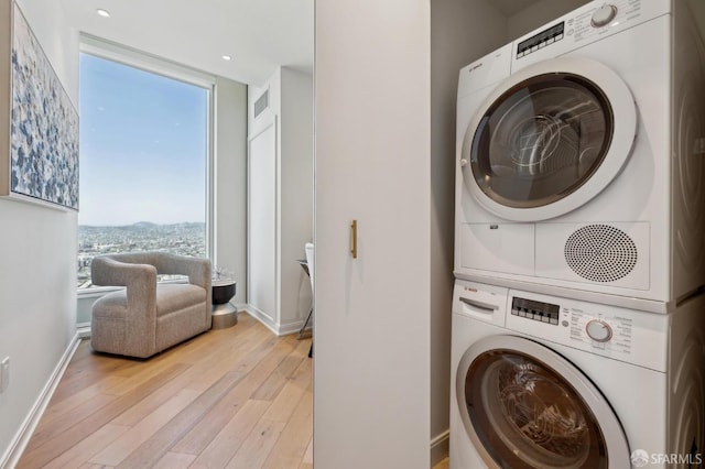401 Harrison St Unit 45C, San Francisco, CA 94105 - laundry room featuring stacked washer and clothes dryer, light wood finished floors, and baseboards