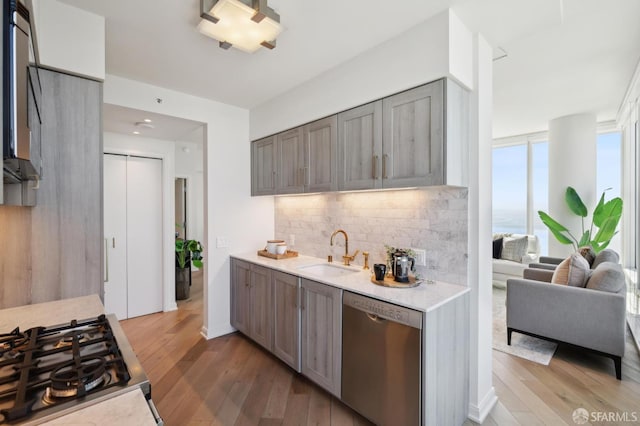 401 Harrison St Unit 45C, San Francisco, CA 94105 - kitchen with stainless steel appliances, a sink, light countertops, decorative backsplash, and light wood-style floors