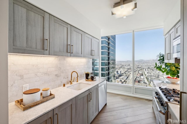 401 Harrison St Unit 45C, San Francisco, CA 94105 - kitchen with a sink, appliances with stainless steel finishes, tasteful backsplash, light wood-style floors, and light stone counters