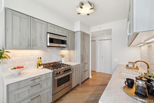 401 Harrison St Unit 45C, San Francisco, CA 94105 - kitchen with stainless steel appliances, a sink, decorative backsplash, gray cabinets, and light wood-style flooring