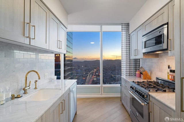401 Harrison St Unit 45C, San Francisco, CA 94105 - kitchen with appliances with stainless steel finishes, a sink, light wood-type flooring, decorative backsplash, and light stone countertops