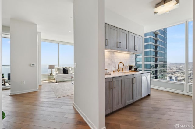 401 Harrison St Unit 45C, San Francisco, CA 94105 - bar area featuring healthy amount of natural light, stainless steel dishwasher, hardwood / wood-style floors, and tasteful backsplash