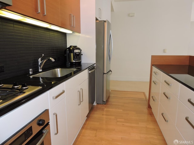 kitchen featuring light hardwood / wood-style flooring, stainless steel appliances, white cabinetry, and decorative backsplash